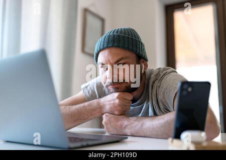 Young adult man watching vlog on the internet and smiling. Stock Photo