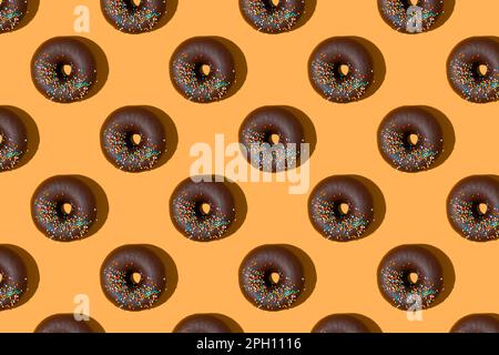 Chocolate donuts pattern isolated on orange background. Bakery, doughnut, treat, sweet food. Top view, flat lay, wallpaper, backdrop Stock Photo