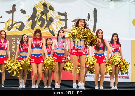 Group of young Japanese women in skimpy cheerleader costumes on an outdoor stage performing Yosakoi dancing at the annual Kumamoto Kyusyu gassai dance festival, itself part of the Spring Festival. Stock Photo