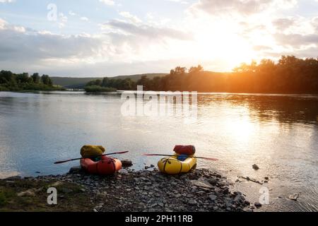 Orange and yellow packrafts rubber boats with padles on a sunrise Dnister river. Packrafting background. Active lifestile concept Stock Photo