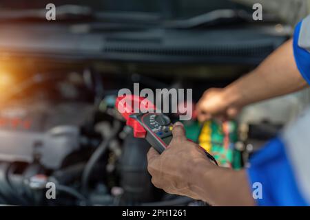 Close up technician uses multimeter voltmeter to check voltage level in car battery. Service and Maintenance car battery. Stock Photo