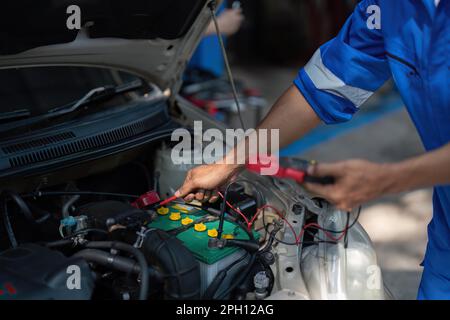 Close up technician uses multimeter voltmeter to check voltage level in car battery. Service and Maintenance car battery. Stock Photo