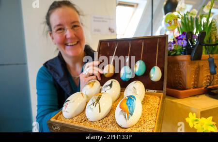 25 March 2023, Lower Saxony, Lübeln: Kirstin Rüter, artisan, holds a box of eggs she has painted. At the traditional Easter egg market at the Rundlingsmuseum, Easter eggs of different types and sizes are on display, decorated and painted. Photo: Philipp Schulze/dpa Stock Photo