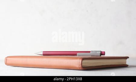 pencil on a note book or leather diary placed on white table top against a textured wall background, education and journaling concept with copy space Stock Photo