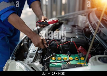 Close up technician uses multimeter voltmeter to check voltage level in car battery. Service and Maintenance car battery. Stock Photo
