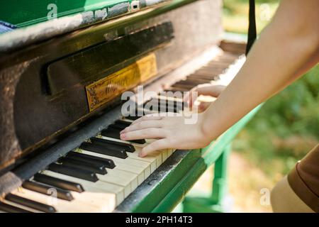 Female hands playing on old piano in public park, outdoor art music performance close up view. Playing on classic piano at outdoor concert green grass Stock Photo