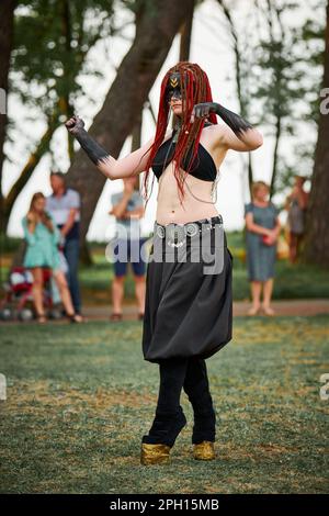 Mythological dancing girl faun on green lawn in public park outdoor art dancing event with mythological atmosphere. Girl in image of mythical creature Stock Photo