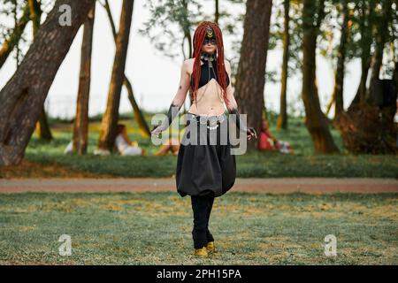 Mythological dancing girl faun on green lawn in public park outdoor art dancing event with mythological atmosphere. Girl in image of mythical creature Stock Photo