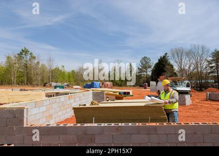 Building engineer with extensive experience in safety holding blueprint their hands while working on construction site monitoring progress of construction Stock Photo