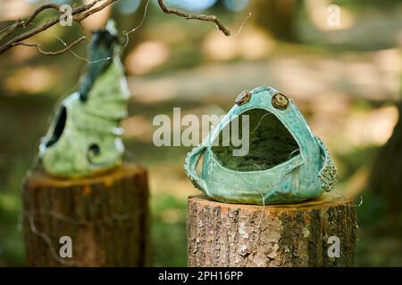 Decorative vases art objects in marine style on tree stump at outdoor art exhibition green forest background, dreamlike funny figure. Green craft bowl Stock Photo