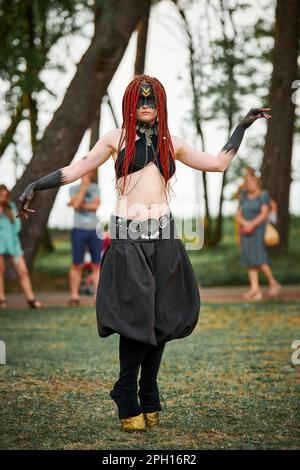 Mythological dancing girl faun on green lawn in public park outdoor art dancing event with mythological atmosphere. Girl in image of mythical creature Stock Photo