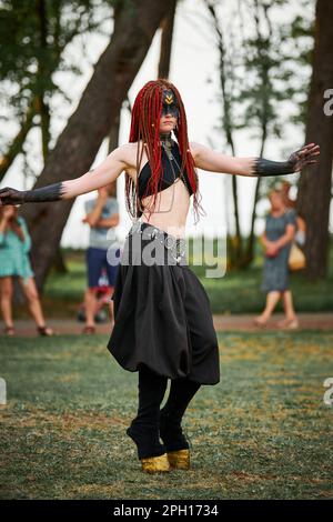 Mythological dancing girl faun on green lawn in public park outdoor art dancing event with mythological atmosphere. Girl in image of mythical creature Stock Photo