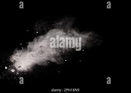 Split debris of  stone exploding with white powder against black background. Stock Photo