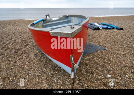 Front on view of a red fishing boat on the stony beach of Dunwich on the Suffolk coast Stock Photo