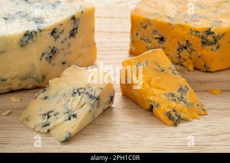 Piece of English Shropshire Blue cheese and a piece of Stilton cheese on a cutting board for a snack close up Stock Photo