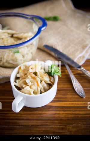 cooked dumplings with potatoes and fried onions, in a bowl on a wooden table. Stock Photo