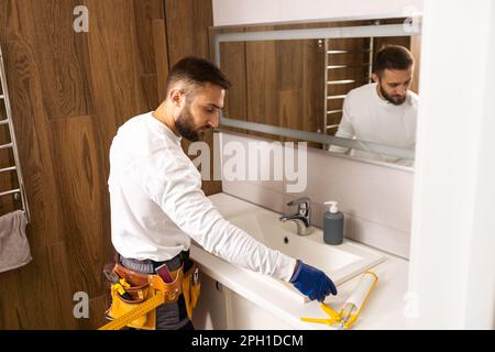 a worker installs a wash basin in a bathroom. Stock Photo