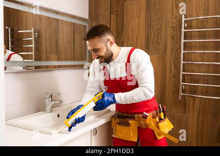 a worker installs a wash basin in a bathroom. Stock Photo