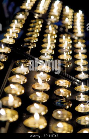 Votive candle rack or prayer candle rack with rows of flickering lit candles in Worcester Cathedral, England, United Kingdom. Photo taken on 28th of J Stock Photo