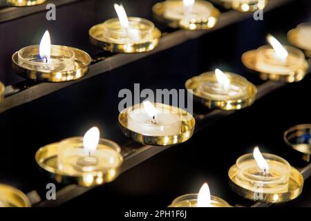 Votive candle rack or prayer candle rack with rows of flickering lit candles in Worcester Cathedral, England, United Kingdom. Photo taken on 28th of J Stock Photo