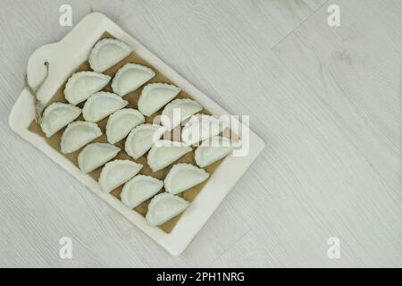 Dumplings with potatoes on the kitchen board. Dumplings with potatoes is a traditional Ukrainian dish. Fast food. Stock Photo