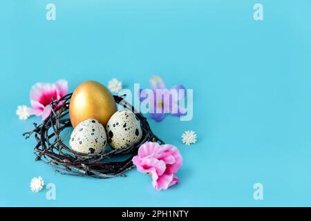Golden Easter eggs in a nest on a blue background with space. Easter decoration, colored eggs in a bird nest with flowers. Turquoise pastel background Stock Photo