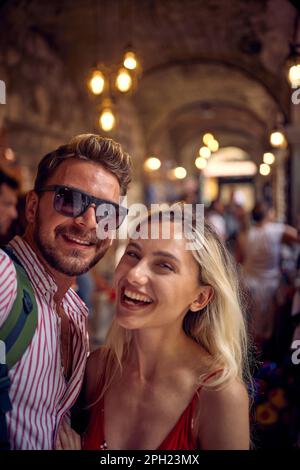 Couple taking selfie at street shop. Tourists on vacation walking through street bazar. Holiday, fun, shopping, lifestyle concept. Stock Photo