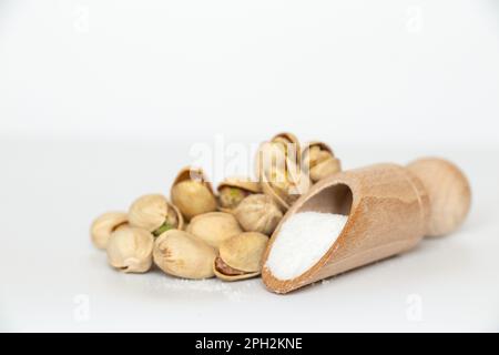 Bunch of pistachios and wooden spoon with salt on white background Stock Photo