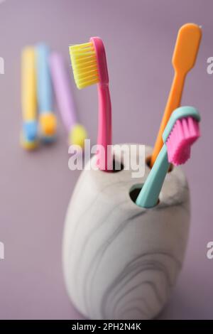 colorful toothbrushes in white mug against a wall Stock Photo - Alamy