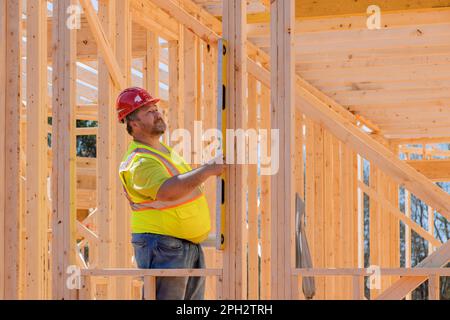Construction engineer checking leveling quality of wooden frame beams work using level on construction site. Stock Photo
