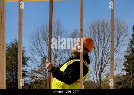 As construction engineer checking leveling quality of wooden frame beams work using level on construction site. Stock Photo