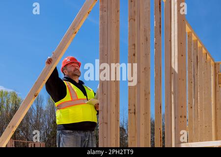 Engineers checking leveling quality of wooden beams using level on construction site as part quality control process. Stock Photo