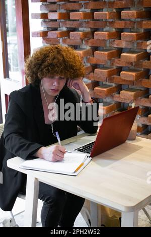 Non binary man business worker talking on smartphone writing on ...