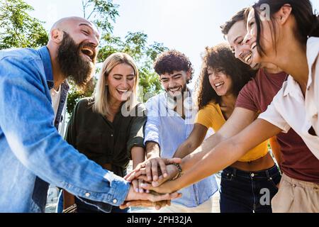 Multiracial young people stacking hands showing unity. Stock Photo
