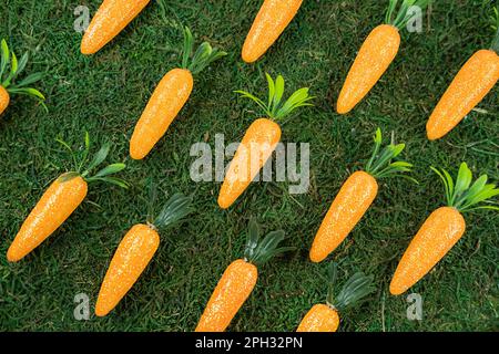 Easter pattern background made of decorative carrots on natural organic texture. Minimal festive spring concept. Stock Photo
