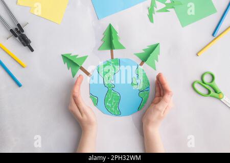 earth cut from paper around trees earth day concept kid's paper craft Stock Photo