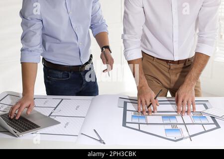 Architects working with construction drawings at table in office, closeup Stock Photo