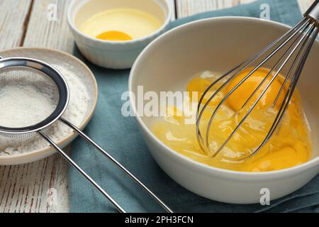 Whisking eggs in bowl on wooden table, closeup Stock Photo