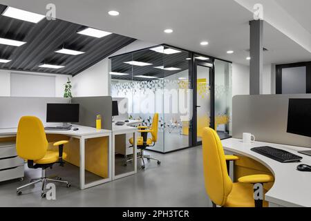 It office with workplaces for employees developers with yellow chairs. Computer for coding room. Stock Photo