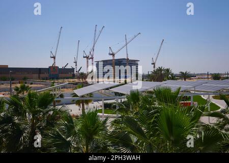 A big construction site with cranes, next to the shopping mall. At Masdar City, a pre-planned, green, sustainable, climate change aware community. In Stock Photo