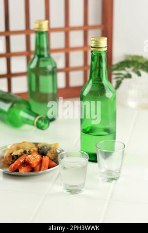 Soju Bottle and Small Glass Cup Served with Anju. Alcoholic Clear Distilled Korean Soju. Stock Photo