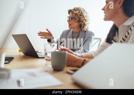 Mature business woman discussing a project with her team in an office. Creative business people having a meeting in a boardroom. business team working Stock Photo