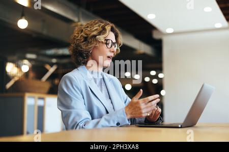 business woman talking on a video call in a coworking office. business woman having an online meeting with her team. Professional business woman doing Stock Photo