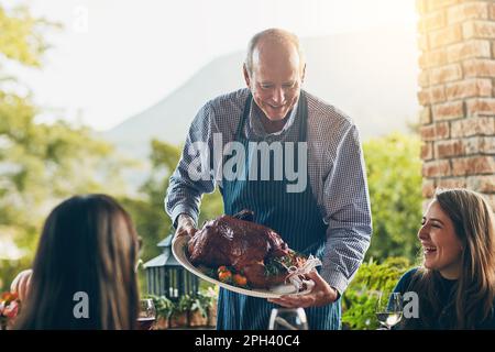 Dad always knew how to make a great turkey. a man bringing a freshly cooked turkey to the dining table. Stock Photo