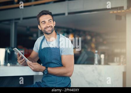 The digital barista. a young man using a digital tablet while working at a coffee shop. Stock Photo