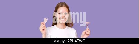 woman facial skin massage with natural guasha roller. Girl enjoy using lifting tool on her face, massaging muscles to reduce tension, rubbing skin care treatment in white t-shirt on purple background Stock Photo