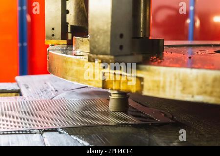 stamp machine that makes holes in a metal sheet in a factory Stock Photo