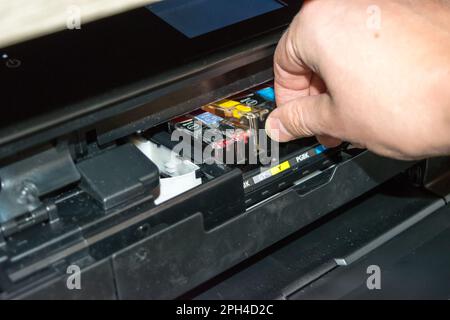 Replacing the ink in the printer, the human hand takes out the cartridge Stock Photo
