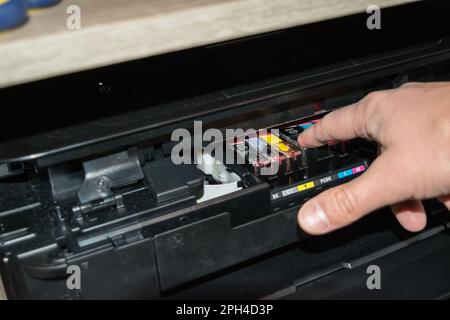 Replacing the ink in the printer, the human hand takes out the cartridge Stock Photo