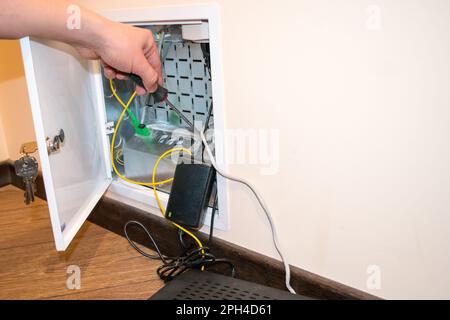 The router box is open, the human hand holds a screwdriver, there is a black router next to it Stock Photo